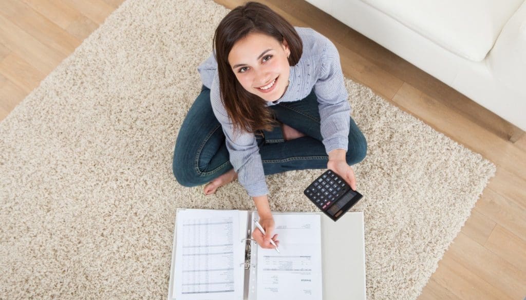 Woman Calculating Home Finances On Rug
